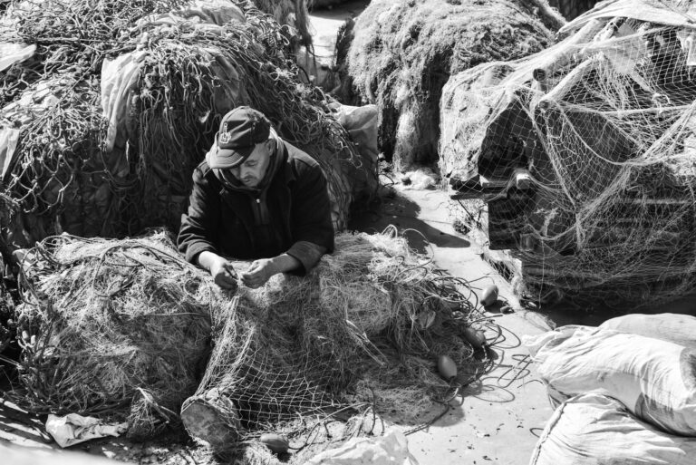 A fisherman mends nets in the bustling port of Essaouira, Morocco.
