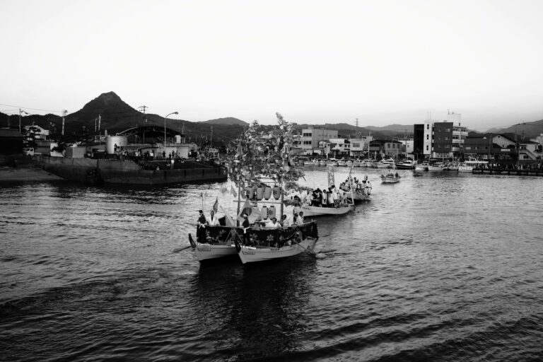 Monochrome view of a Japanese harbor with decorated boats on the water.